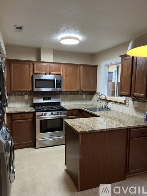 A kitchen with brown cabinets and a granite countertop.