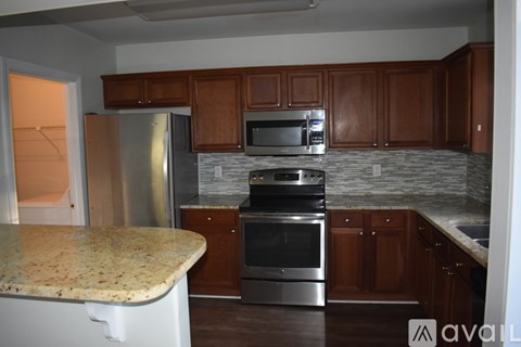 A kitchen with brown cabinets and a granite counter.