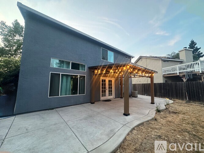A modern house with a grey exterior and a wooden pergola.