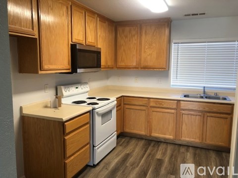 A kitchen with wooden cabinets and a white stove top oven.