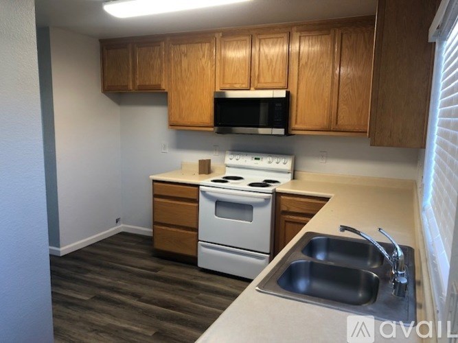 A kitchen with a stove, sink, and cabinets.