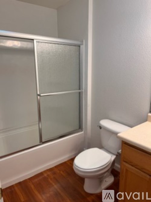 A white toilet sits in a bathroom next to a walk-in shower.