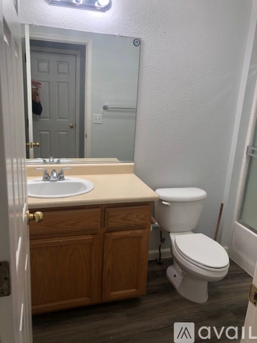 A bathroom with a toilet, sink, and wooden cabinets.