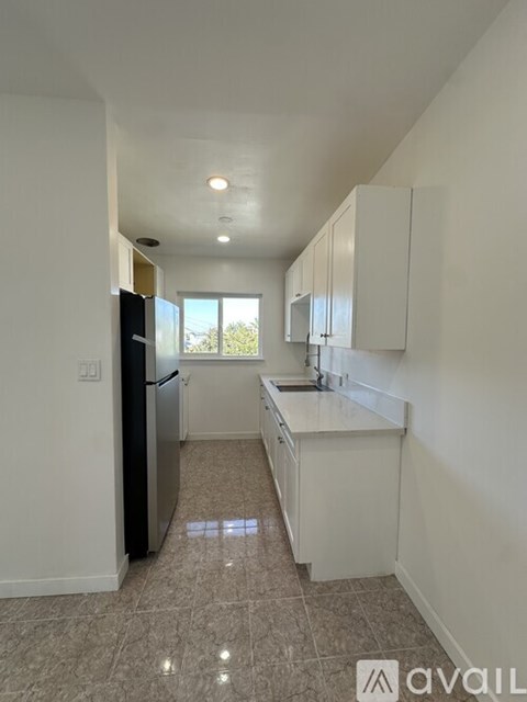 A kitchen with white cabinets and a black refrigerator.