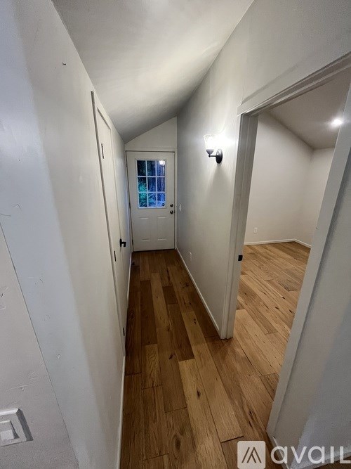 A hallway with wooden floors and white walls.