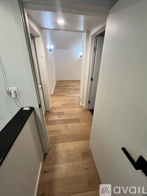 A long hallway with wood floors and white walls.