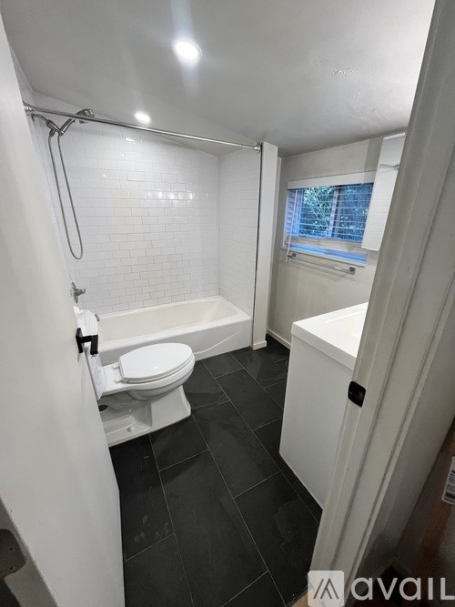 A white toilet with a white bathtub and a window in a bathroom.