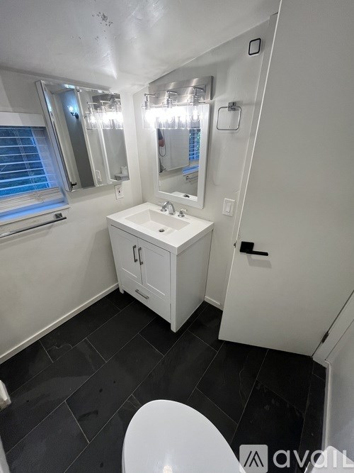 A white bathroom with a toilet, sink, and mirror.