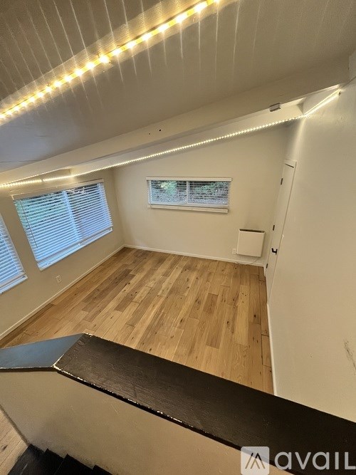 A room with wooden flooring and a window with blinds.
