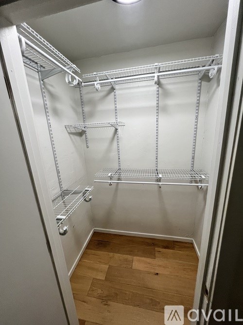 A walk-in closet with shelves and a wooden floor.