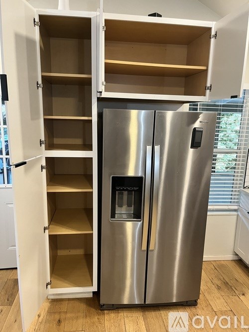 A stainless steel refrigerator with its door open and empty shelves.