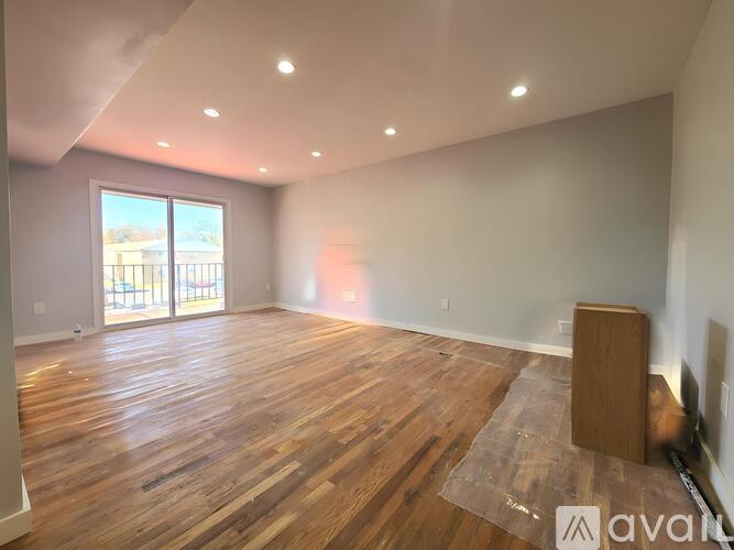 A room with wooden flooring and a large window.