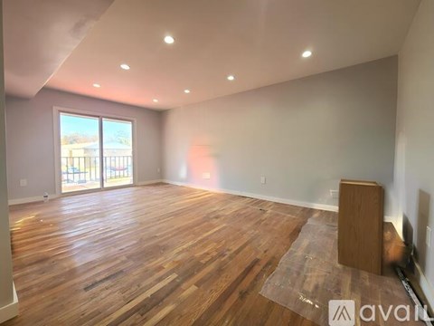 A room with wooden flooring and a large window.