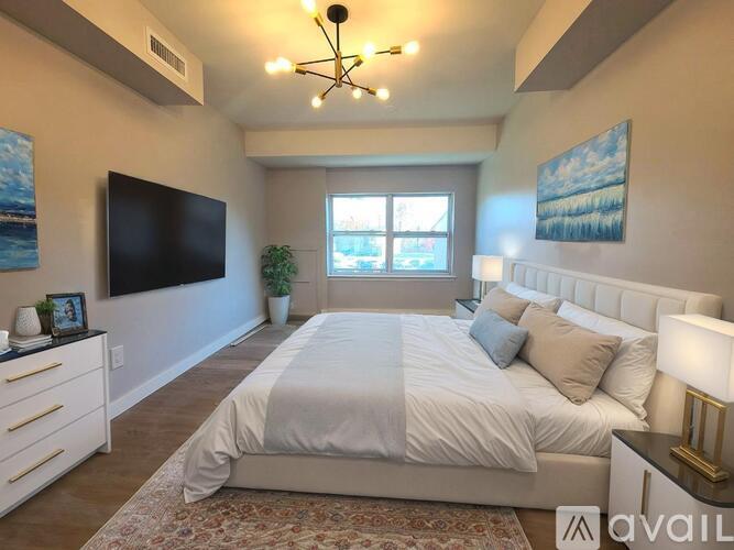 A bedroom with a large bed, a flat screen TV, and a window with a view of the ocean.