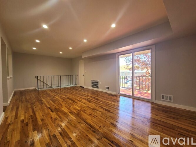 A room with wooden flooring and a sliding glass door leading to a balcony.