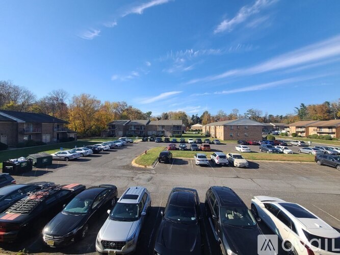 A parking lot with cars parked in rows and a building in the background.