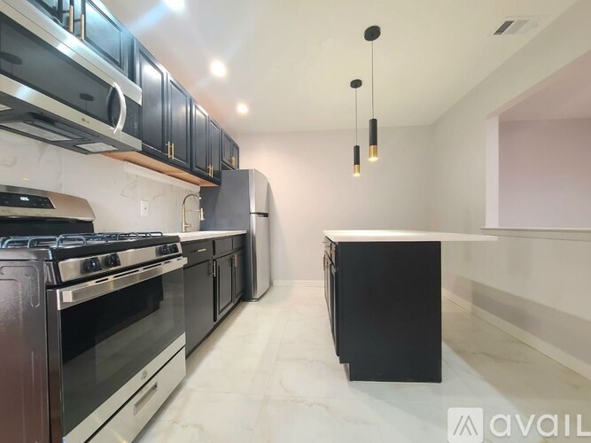 A modern kitchen with black appliances and a marble floor.