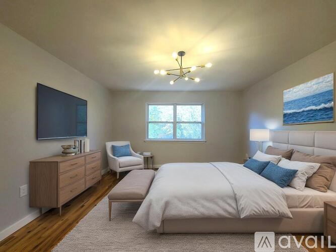 A bedroom with a large bed, a chair, and a painting on the wall.