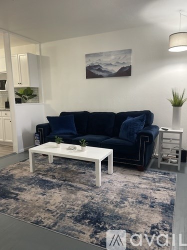 A living room with a blue couch and a white coffee table.