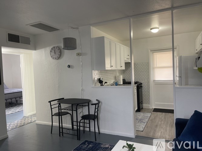 A kitchen with a table and chairs in the foreground and a refrigerator in the background.