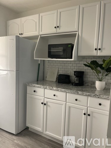 A kitchen with white cabinets and a white fridge.