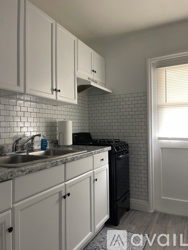 A kitchen with white cabinets and a black dishwasher.