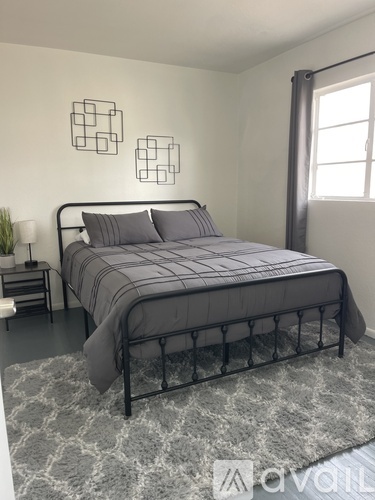 A bedroom with a bed, nightstand, and two wall decorations.