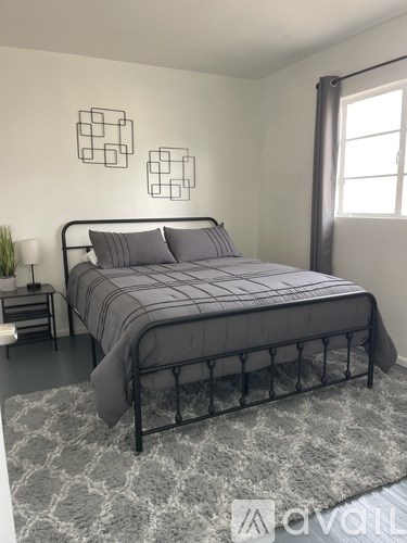 A bedroom with a bed, nightstand, and two wall decorations.