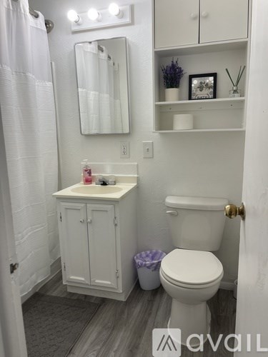 A white bathroom with a toilet, sink, and mirror.
