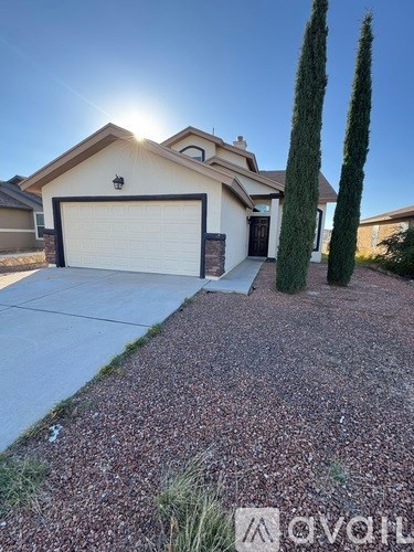 A house with a garage and two trees in front.