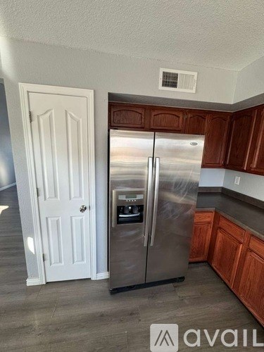A kitchen with a stainless steel refrigerator and wooden cabinets.