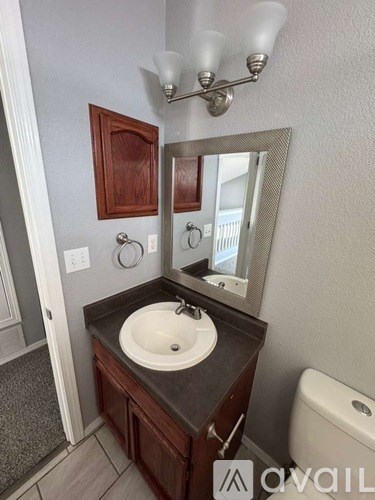 A bathroom with a sink, mirror, and toilet.