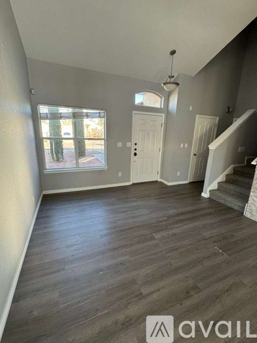A room with wooden floors and a staircase leading to another room.