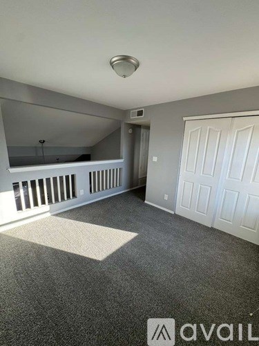 A carpeted room with a white door and a window with blinds.