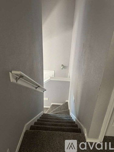 A stairway with a carpeted runner and a metal handrail.