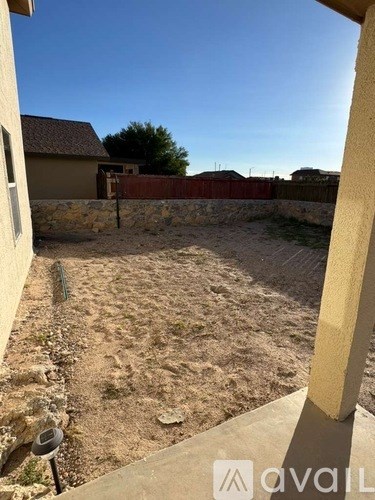A backyard with a dirt ground and a fence.