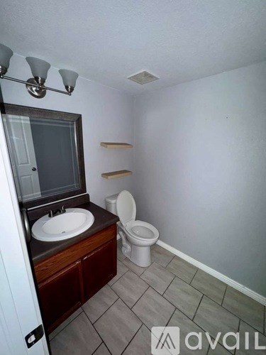 A bathroom with a toilet, sink, and mirror.