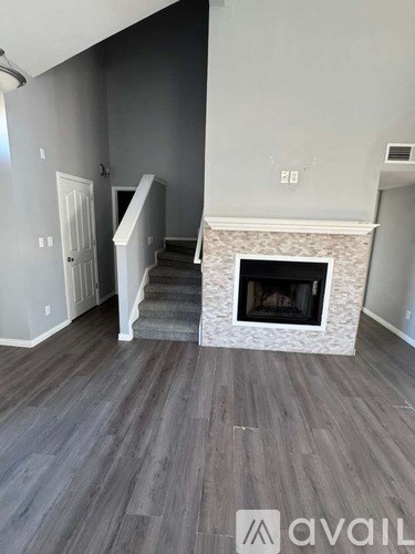 A living room with a fireplace and stairs leading to the upper floor.