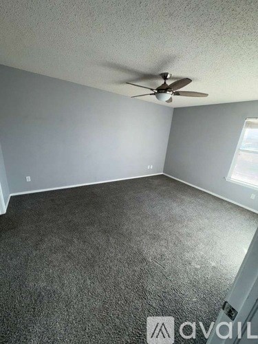 A room with a ceiling fan and carpeted floor.