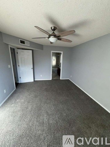 A room with a ceiling fan and carpeted floor.