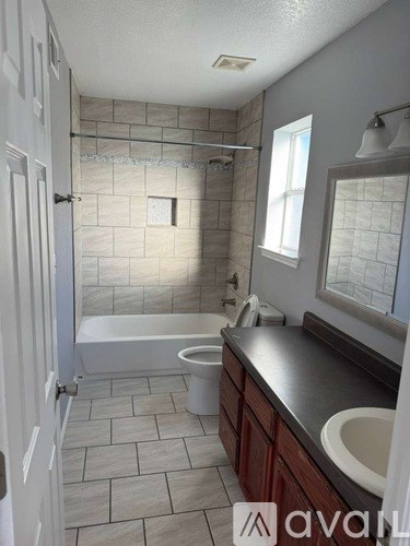 A bathroom with a white tub, sink, and tiled walls.