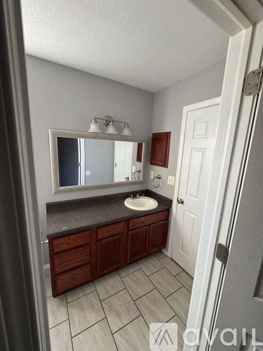 A bathroom with a sink, mirror, and wooden cabinets.