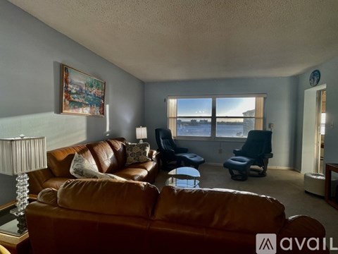 A living room with brown leather couches and a painting on the wall.