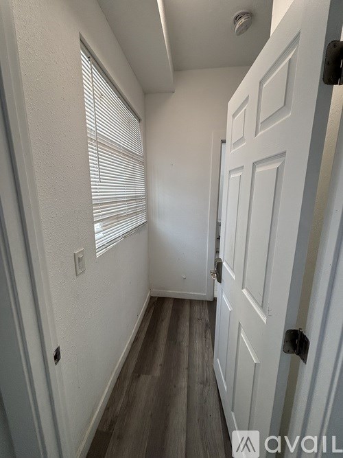 A white door is on the right side of a hallway with a window on the left.