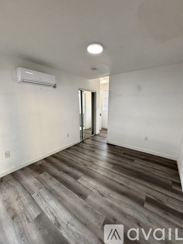 A room with wooden flooring and a wall-mounted air conditioner.