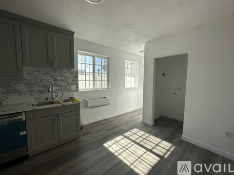 A kitchen with a sink, cabinets, and a window.