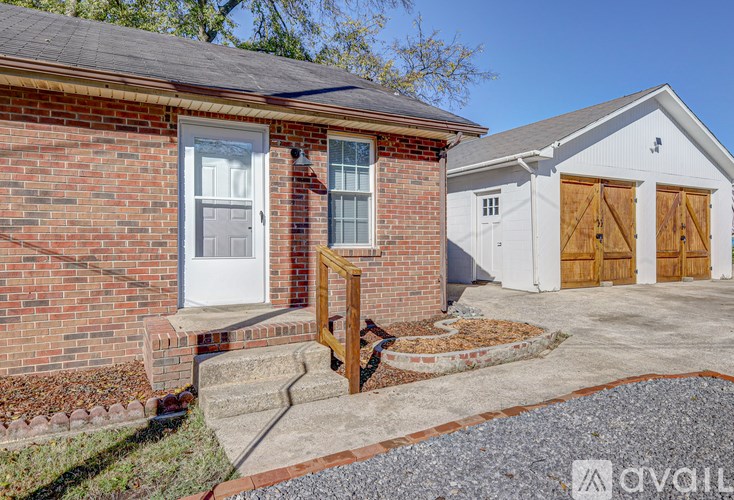 A brick house with a white door and windows is in front of a white building with wooden doors.