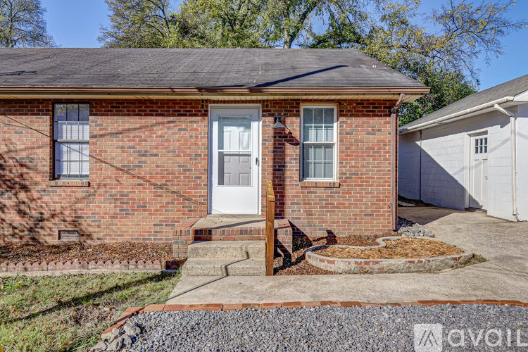 A small red brick house with a white door and windows.
