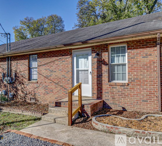 A red brick house with a white door and a wooden railing.