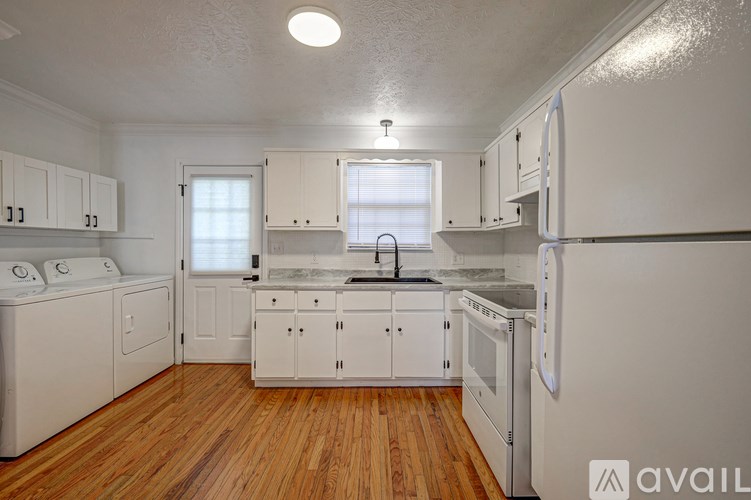 A kitchen with white appliances and wooden floors.